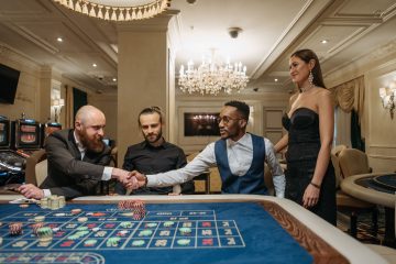 Group of diverse adults engaged at a luxurious casino, shaking hands over a roulette table. — 10 Best Real Money On The Web C