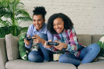 Two teenagers enjoying video games on a couch, showing excitement and joy. — agua bacteriostatica precio 5