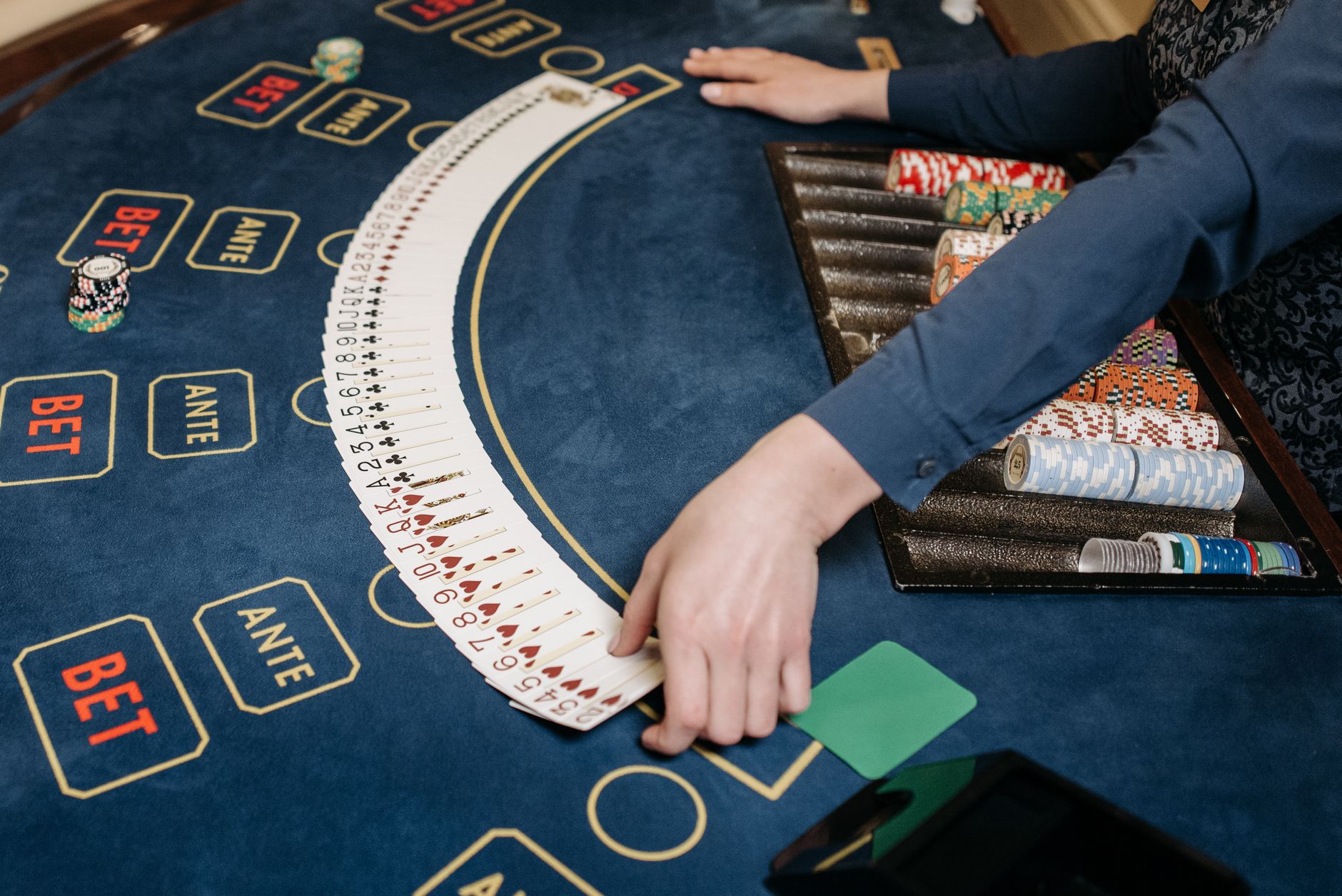 A casino dealer organizing playing cards on a gaming table with chips. Indoors setting. — Best Casino Games Online Of Which P