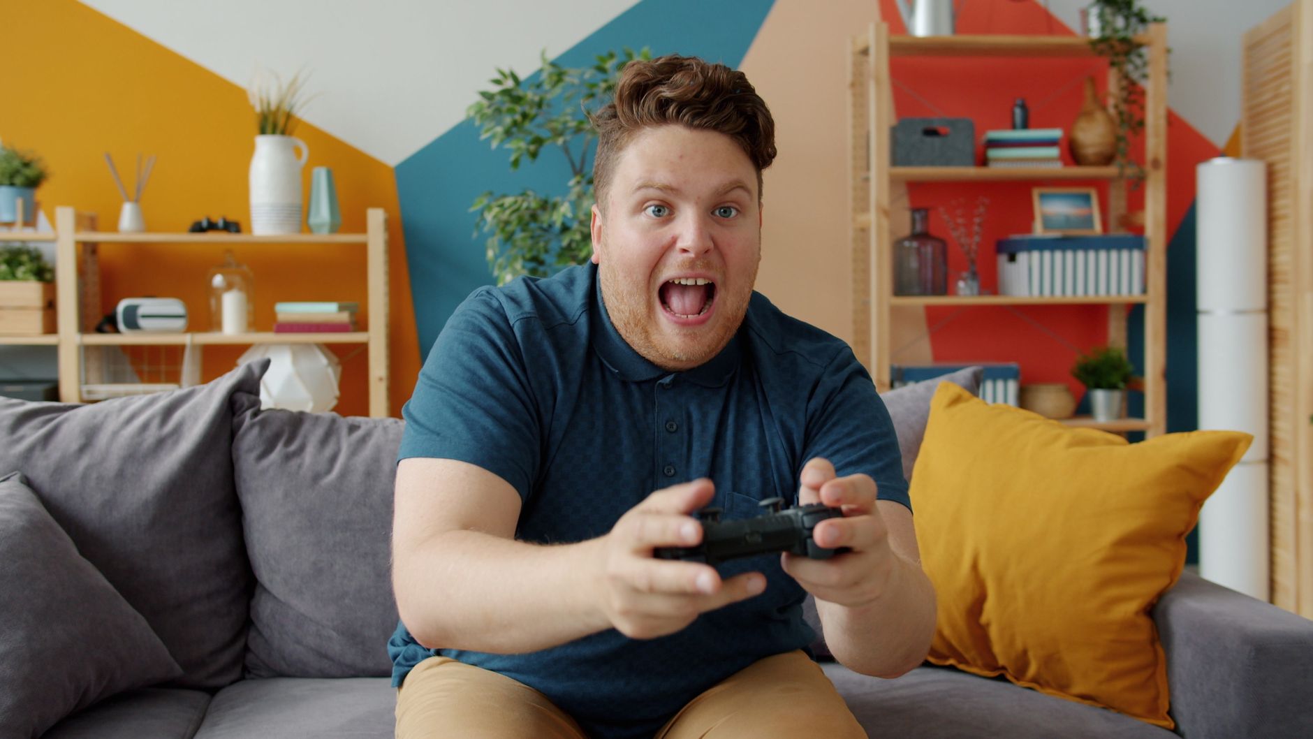 Enthusiastic adult male playing video game on console in colorful, modern living room. — De 6 Bedste Udenlandske Casinoer Ude