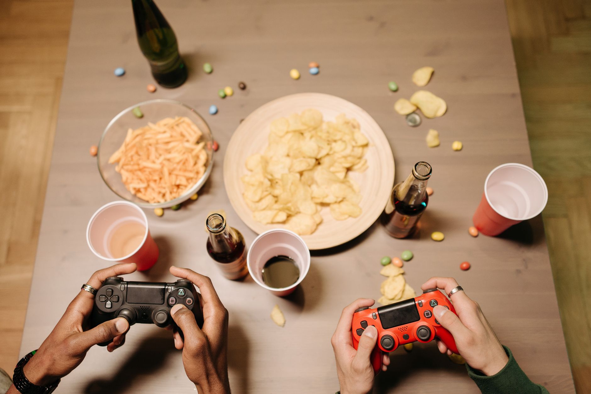 Two gamers playing video games with snacks and drinks on table, a perfect setup for gaming night. — Efectos del Drostanolone