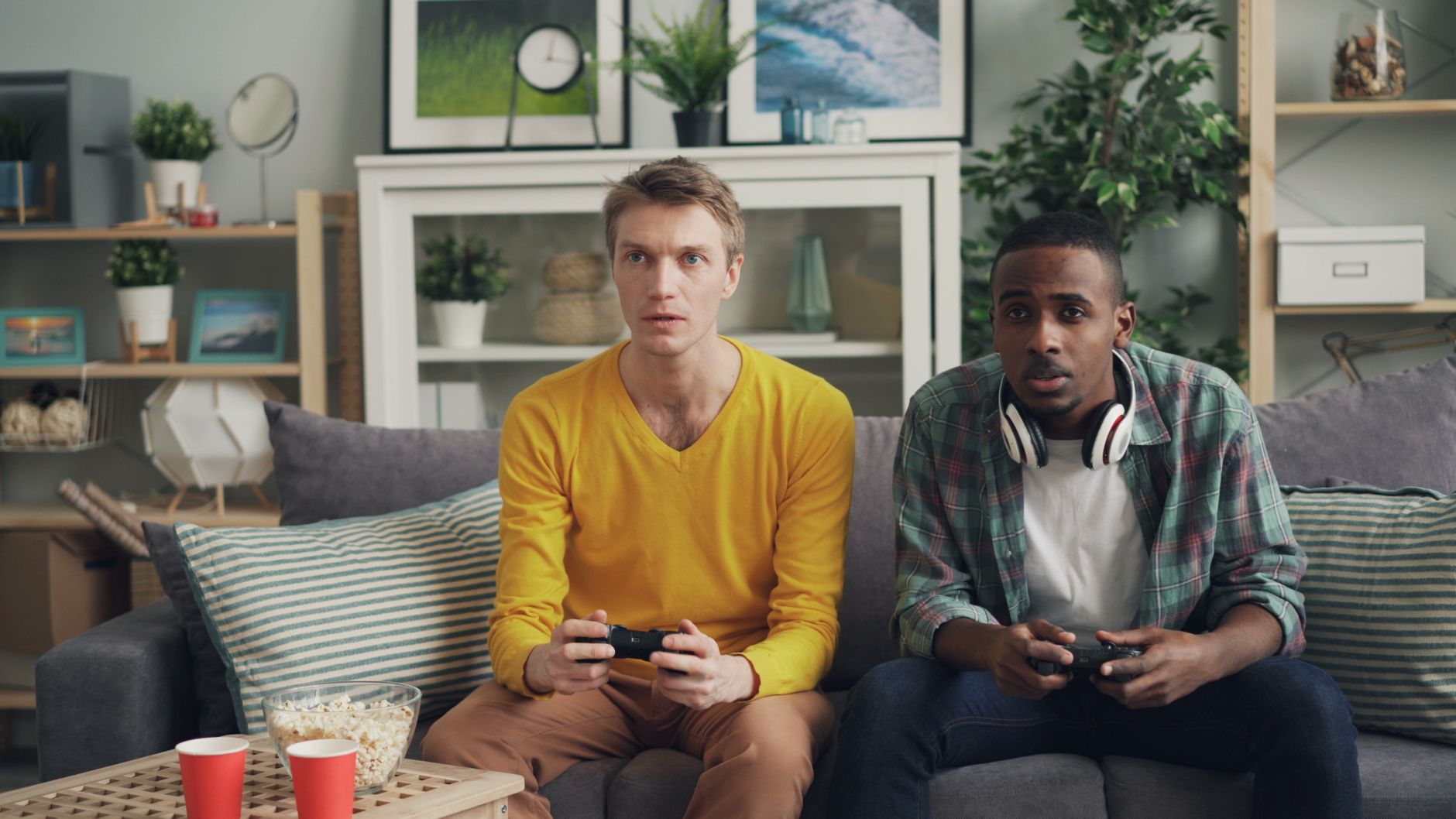 Two friends focus on gaming while relaxing on a couch in a modern living room. — Elevate Your Gambling Experience with PHFUN: