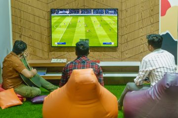 Three friends relaxing and playing a soccer video game indoors on a comfortable game night. — Home to Home: Seamless Relocati