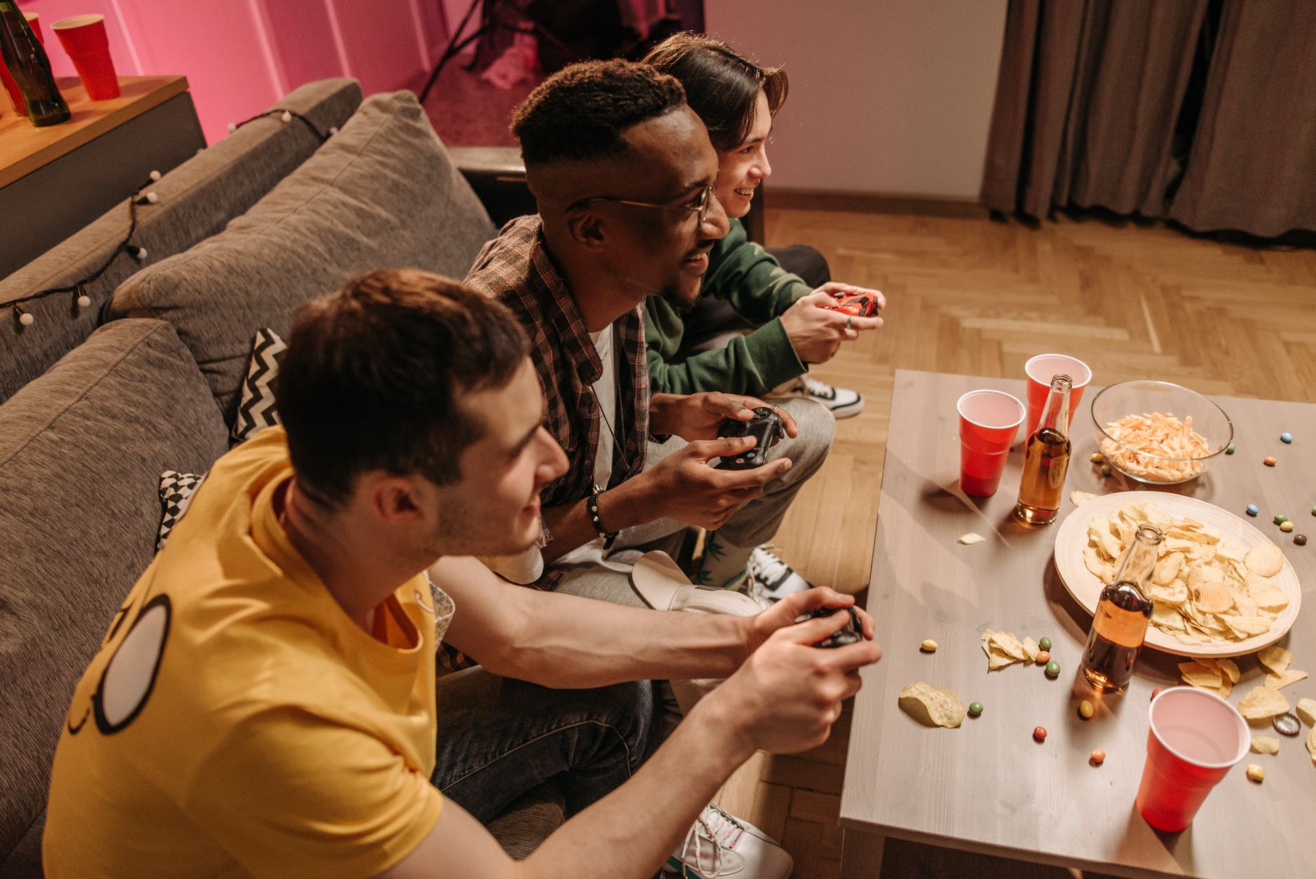 Group of friends playing video games and enjoying snacks indoors. —