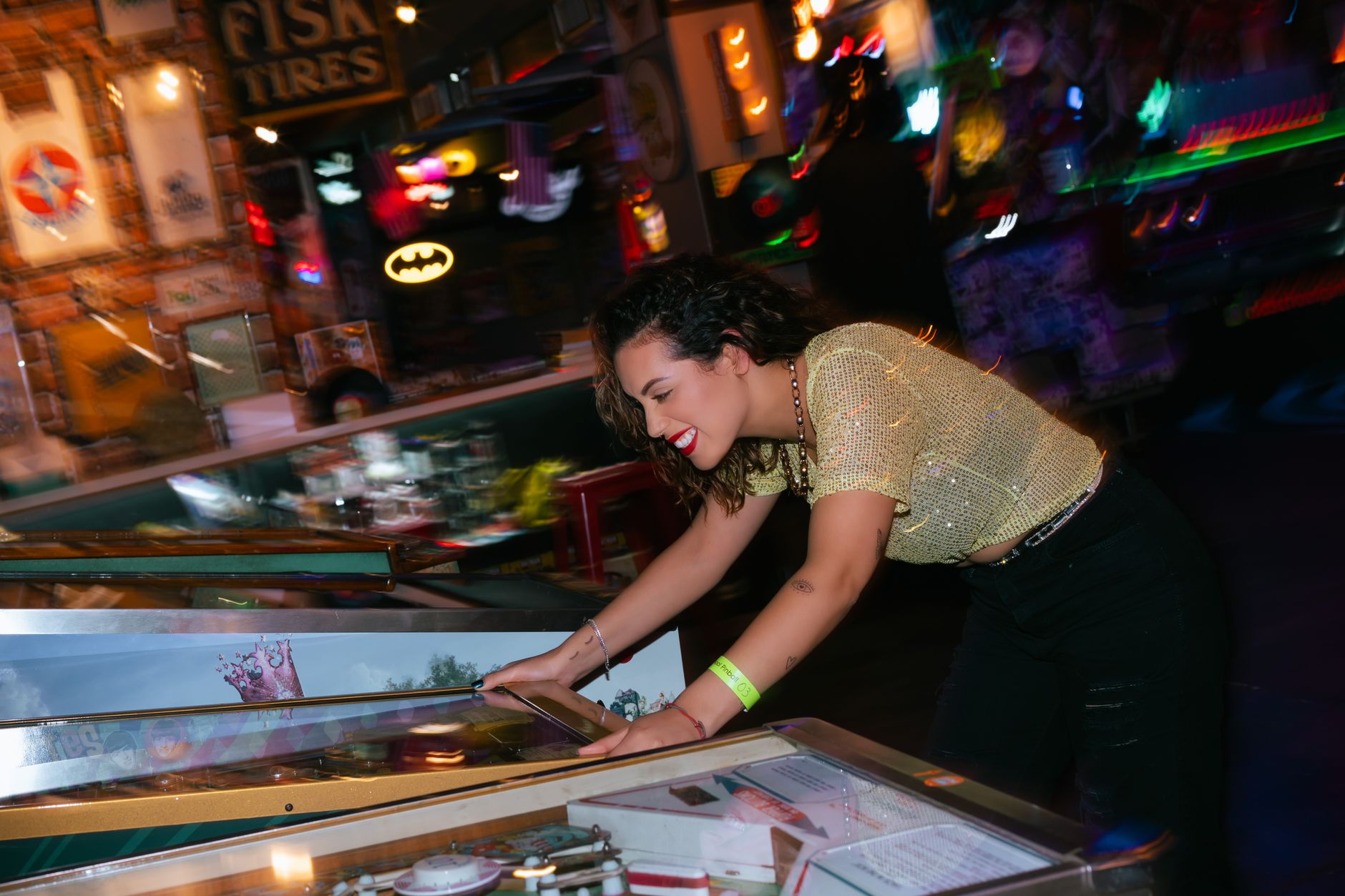 A woman cheerfully plays pinball in a vibrant, colorful arcade setting, embodying fun and entertainment. — Odds Uden Rofus Ca