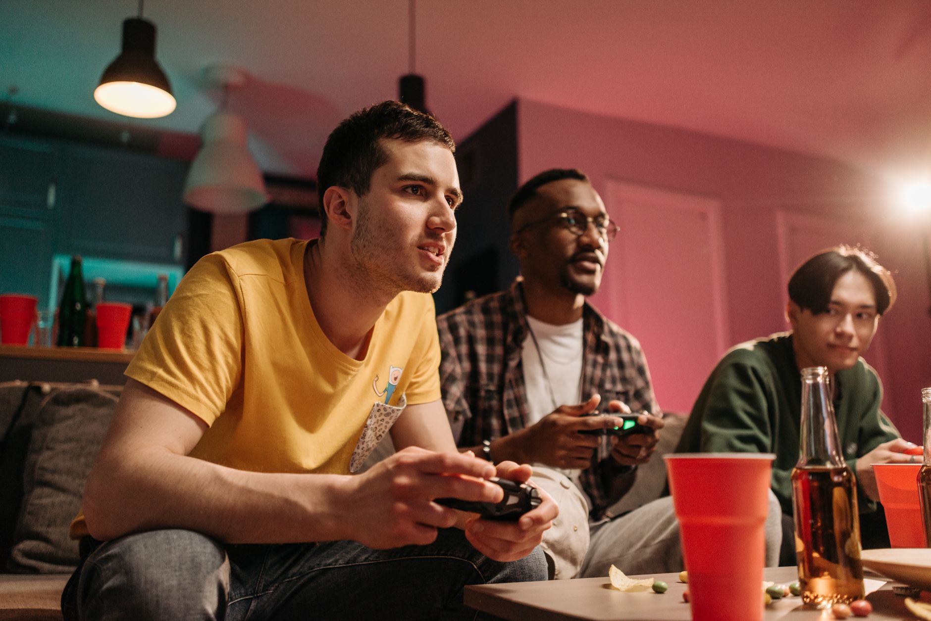 Diverse group of young adults playing video games on a cozy sofa with refreshments. — title