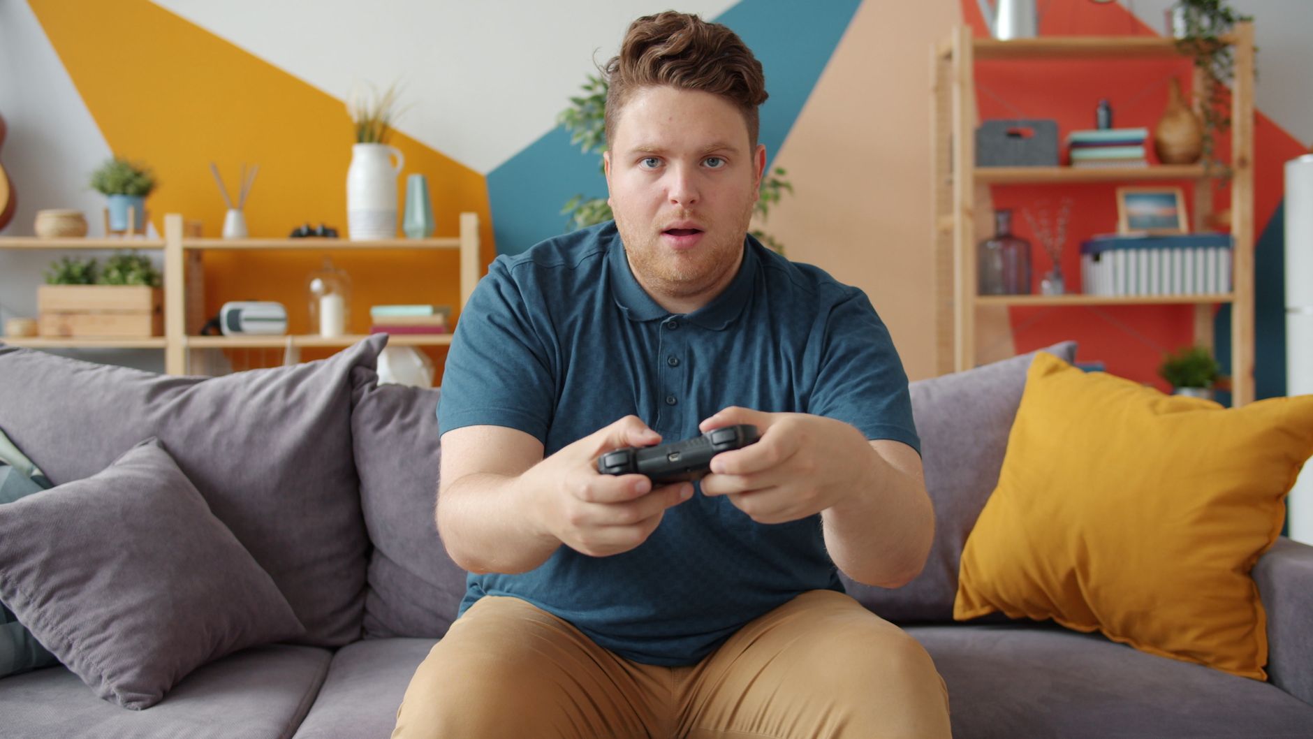 A young man intensely playing video games in a modern living room setting. — title