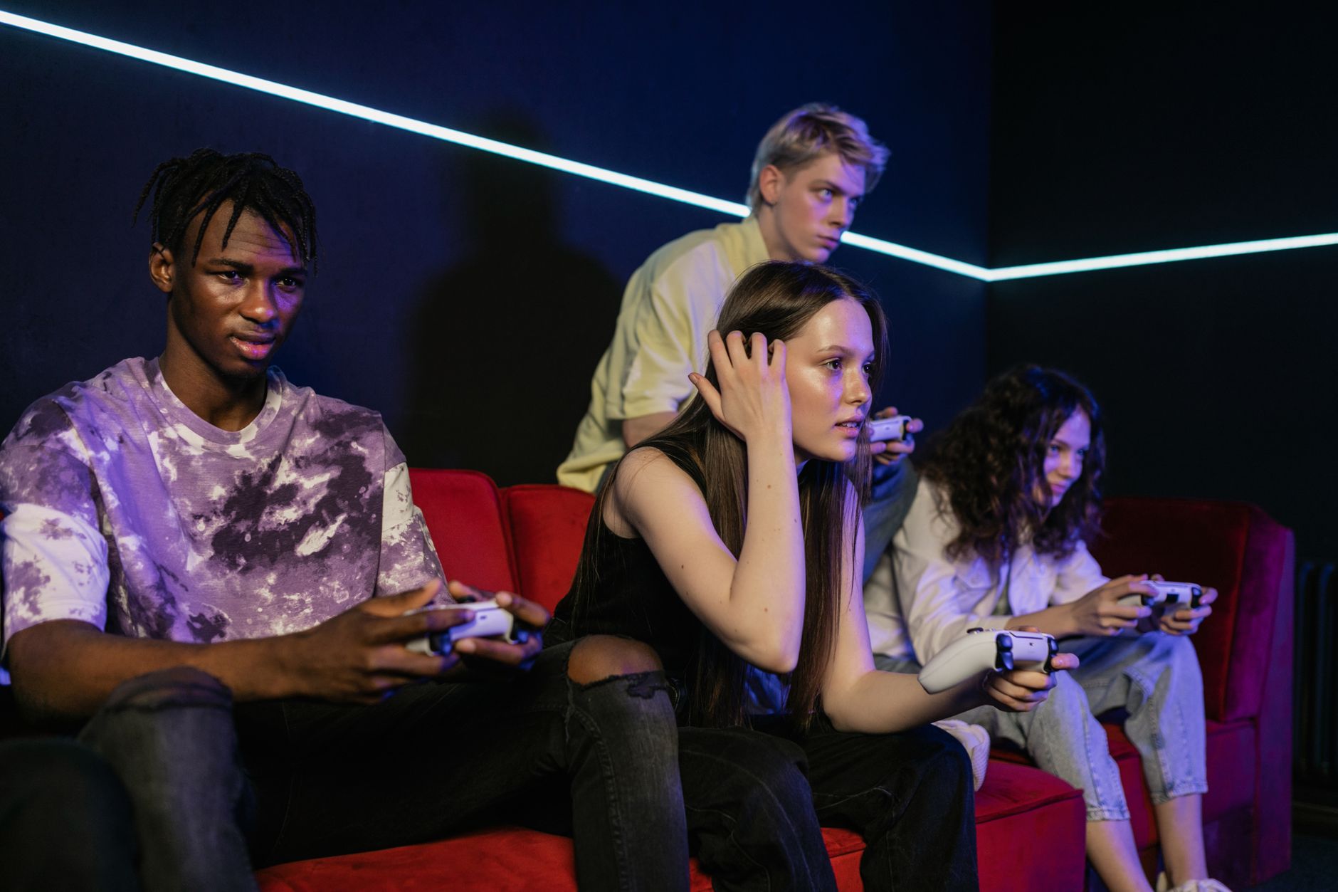 Group of friends enjoying a gaming session on a red sofa with wireless controllers. — Top Internet Casino Bonuses For 2025 Cl