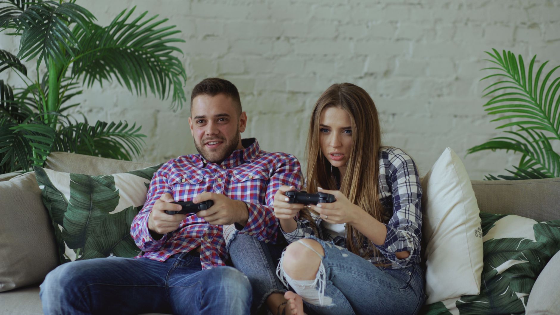 Young couple playing video games intensely on a couch, enjoying leisure time indoors. — XMLRPC Test Post