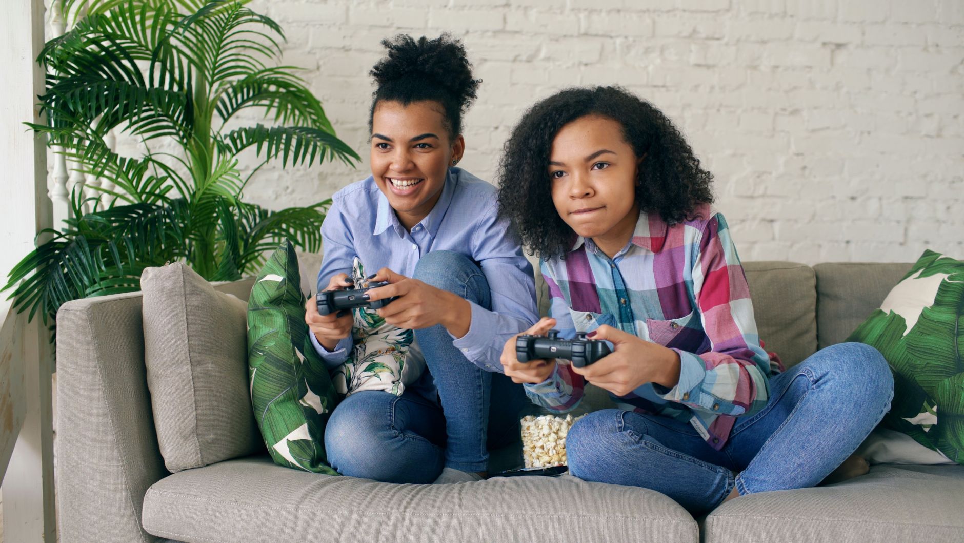Two teenagers playing video games together on a comfortable couch, surrounded by indoor plants. — Your Guide to Using an Onli