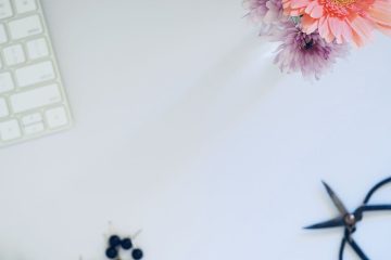 Top view of a workspace with a keyboard, flowers, and small tools