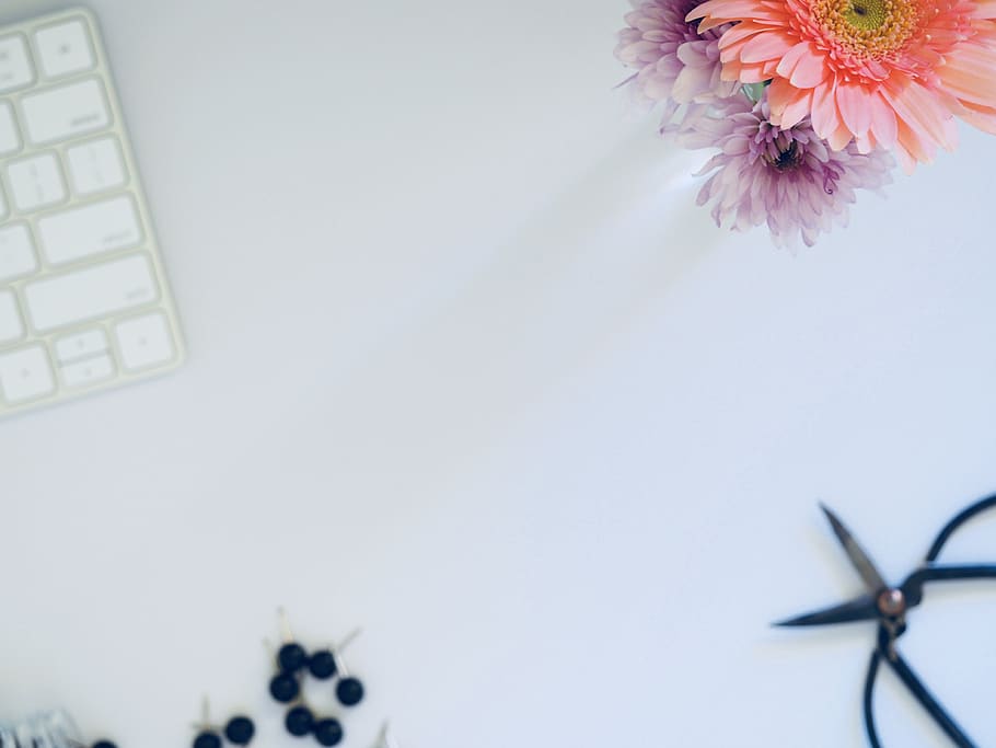 Top view of a workspace with a keyboard, flowers, and small tools
