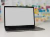 a laptop on a table with a blank screen and colorful sticky notes in the background