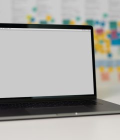 a laptop on a table with a blank screen and colorful sticky notes in the background