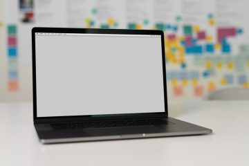 a laptop on a table with a blank screen and colorful sticky notes in the background